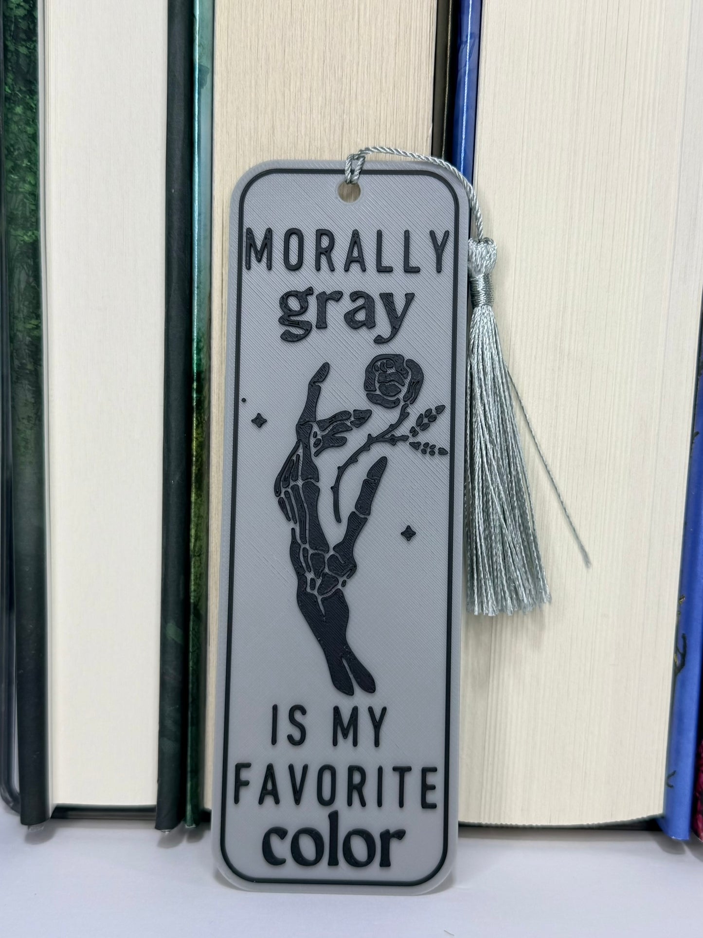 Bookmark with 'Morally gray is my favorite color' text and tassel on a book background