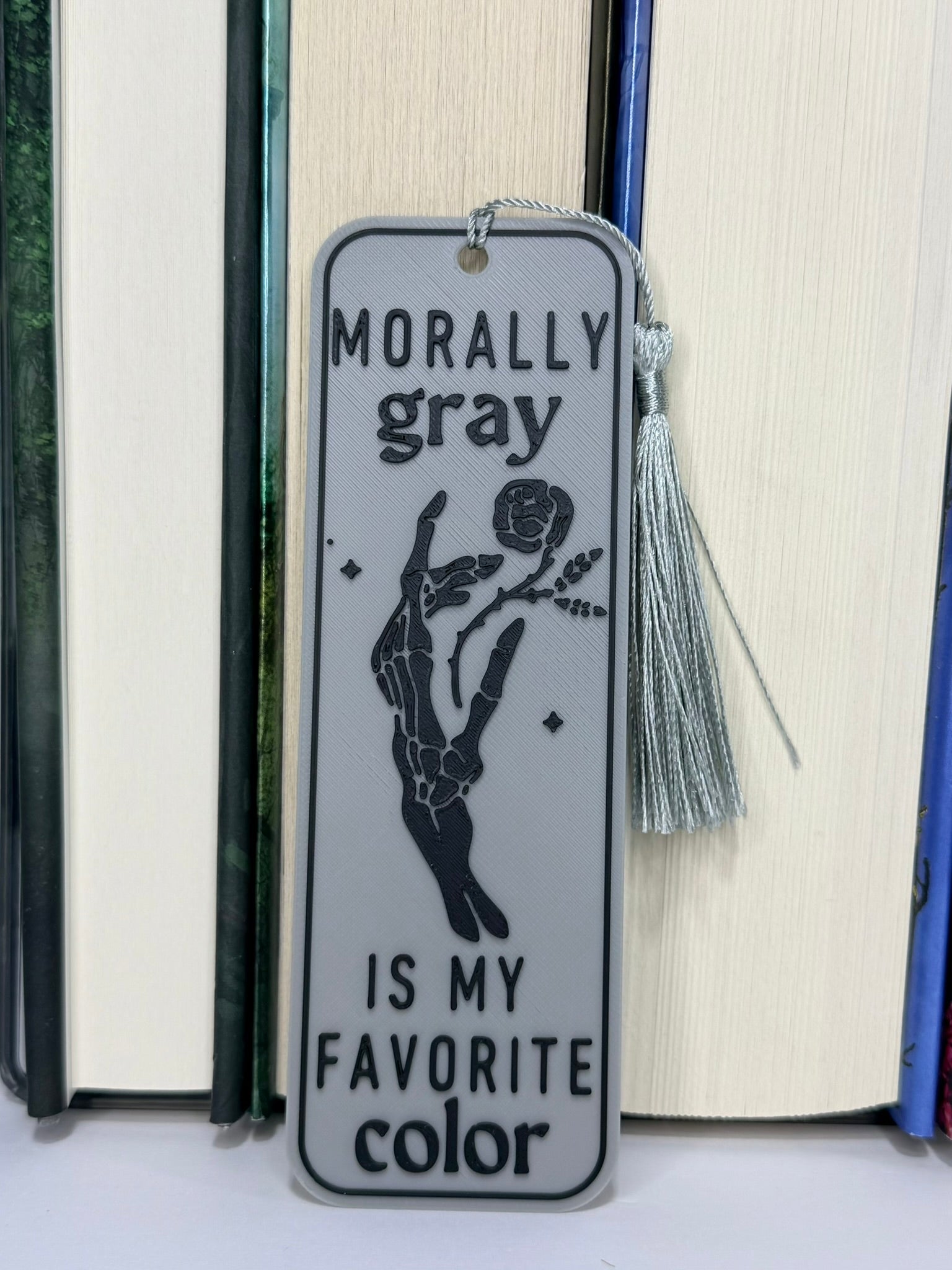 Bookmark with 'Morally gray is my favorite color' text and tassel on a book background