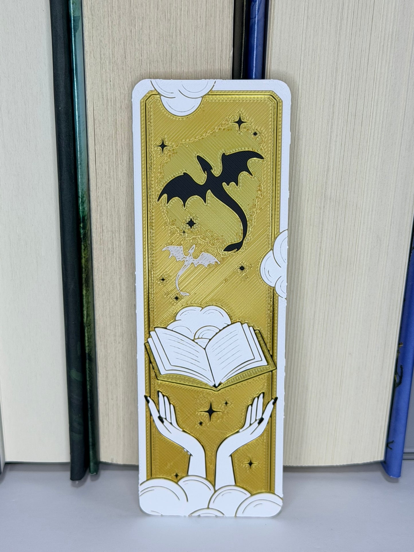 Decorative bookmark with dragon and book design on a gold surface