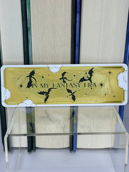 Bookmark with 'In My Fantasy Era' text and silhouette designs on a bookshelf.